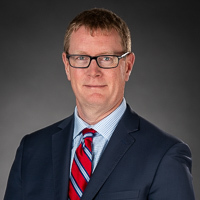 Mark Fisher wearing glasses and a tie